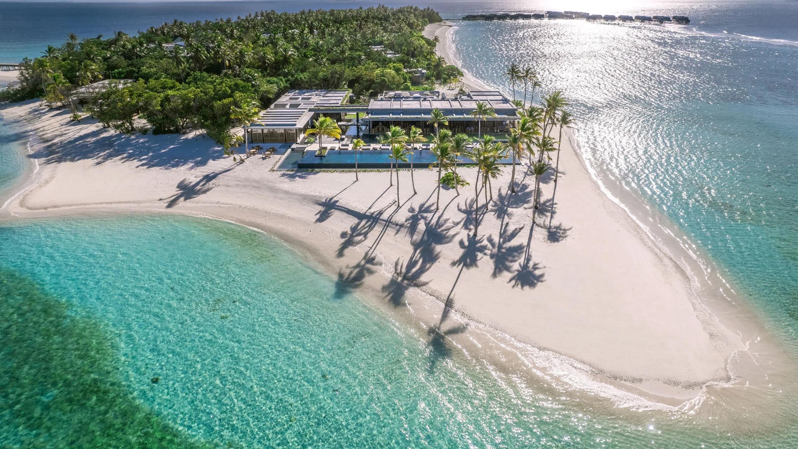 Aerial view of the resort's shared infinity pool beside Seasalt restaurant, the lagoon stretching out beyond