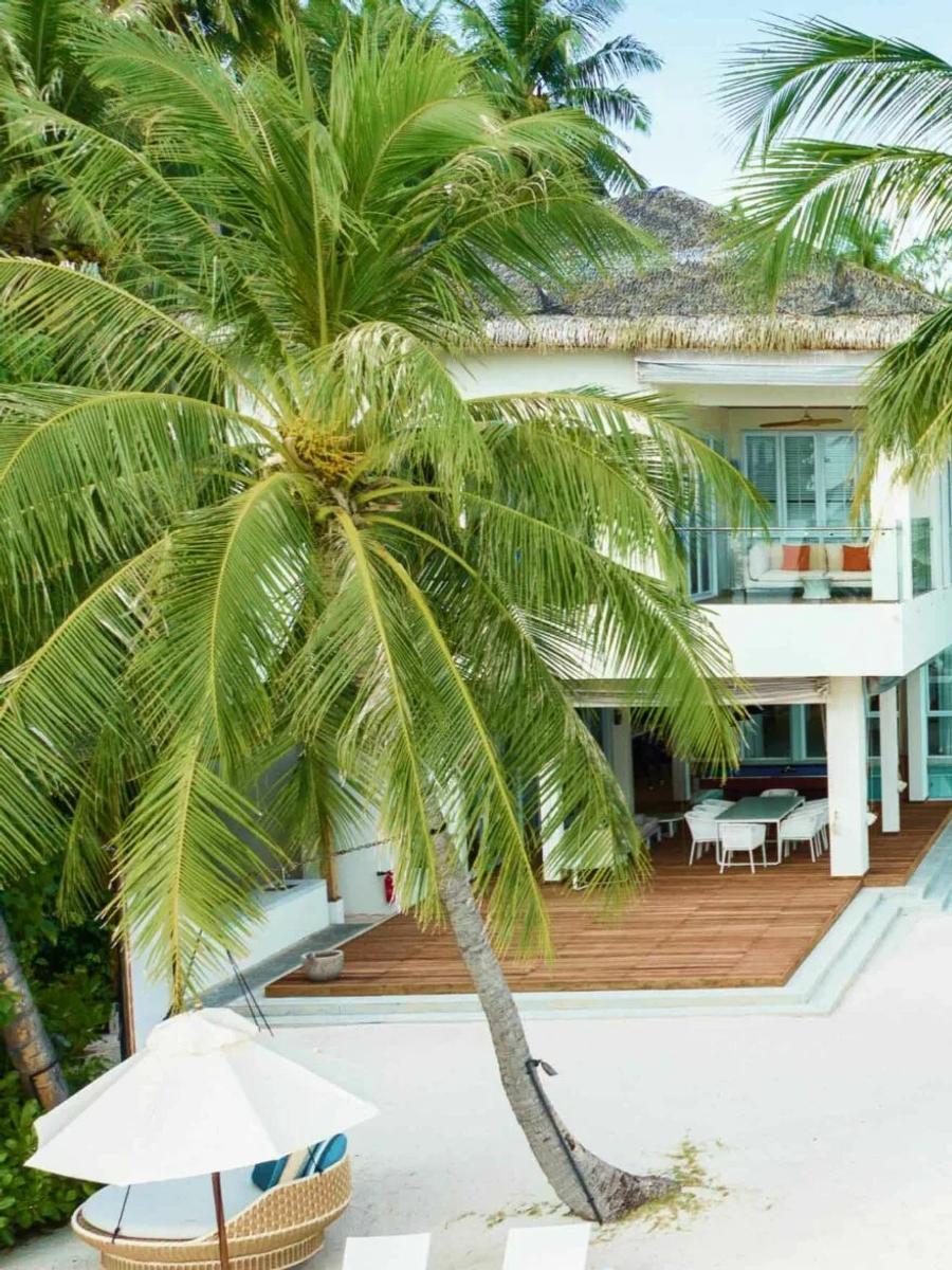 An interior living and dining space inside The Amilla Estate at Amilla, with a timber staircase and views out toward the lagoon