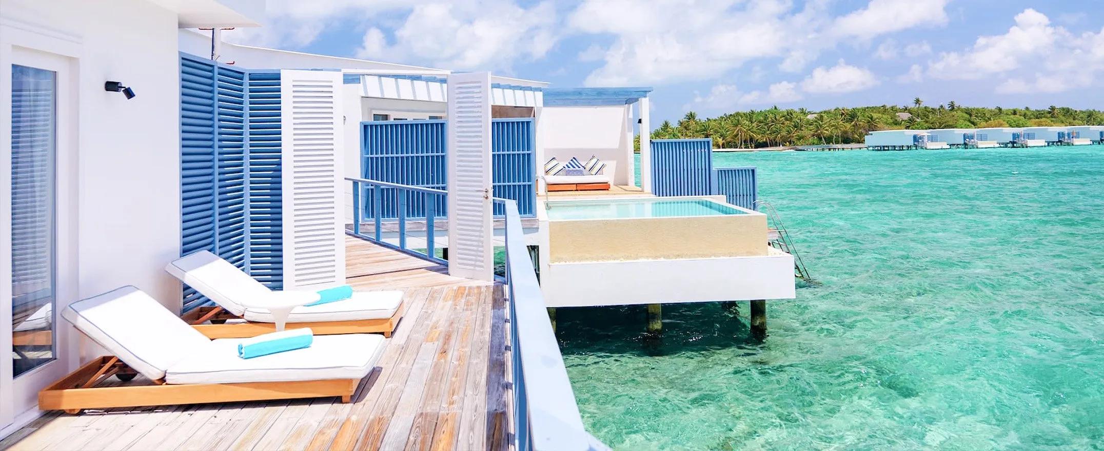 An overwater deck and freshwater infinity pool at a Family Water Pool Villa, Amilla, with sun loungers beside the lagoon