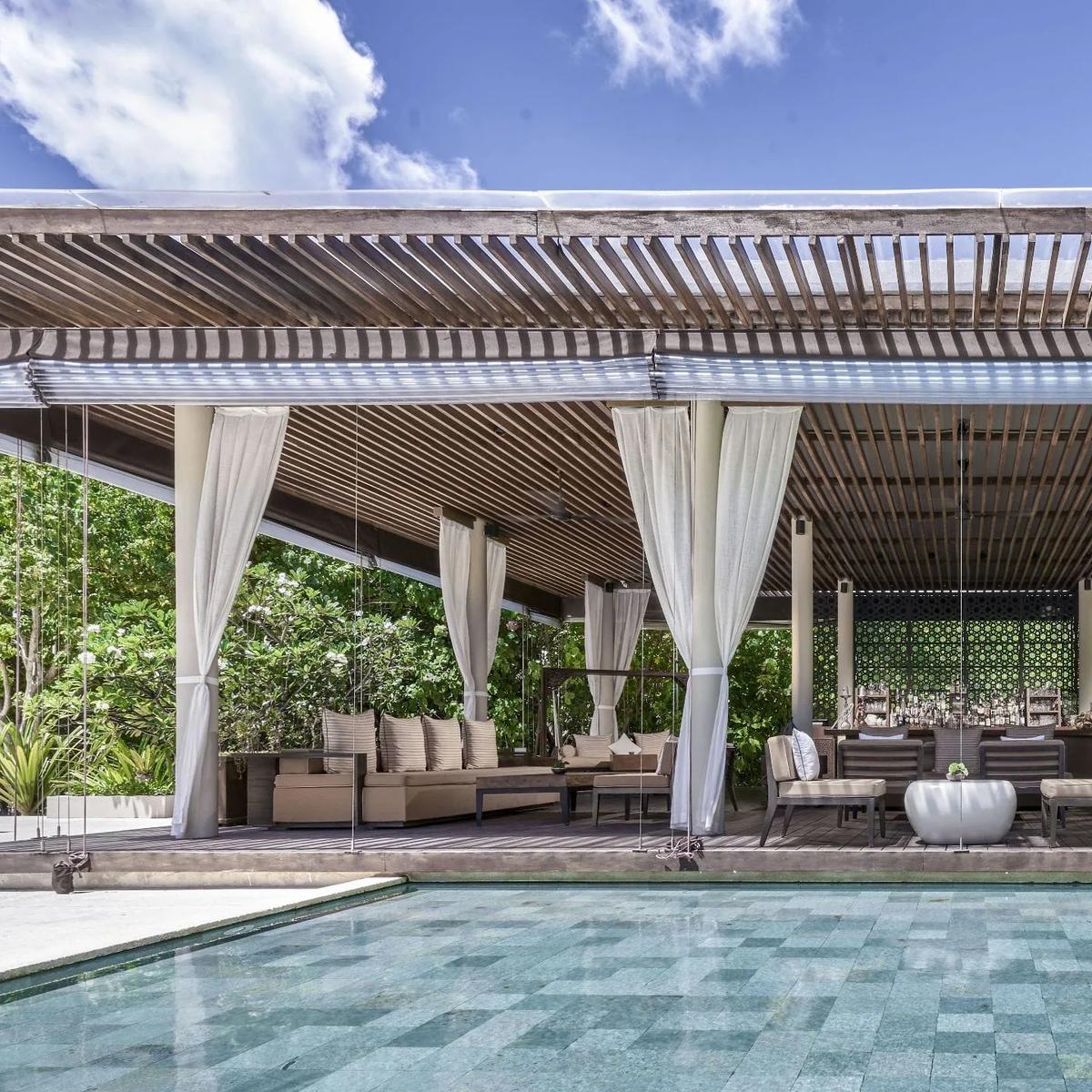 The Bar's open-sided lounge with white curtains, seating arranged beside the main pool