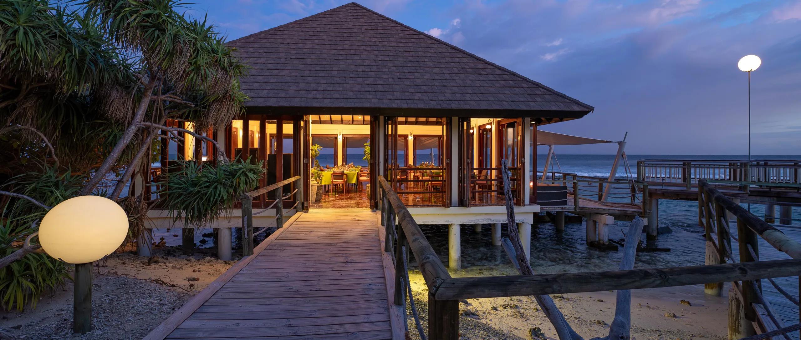 An overwater dining pavilion lit at dusk, its boardwalk reaching out over the lagoon — reused from Just Veg's photography, since Lantern Bar (its overwater extension) has no dedicated images in official site photography