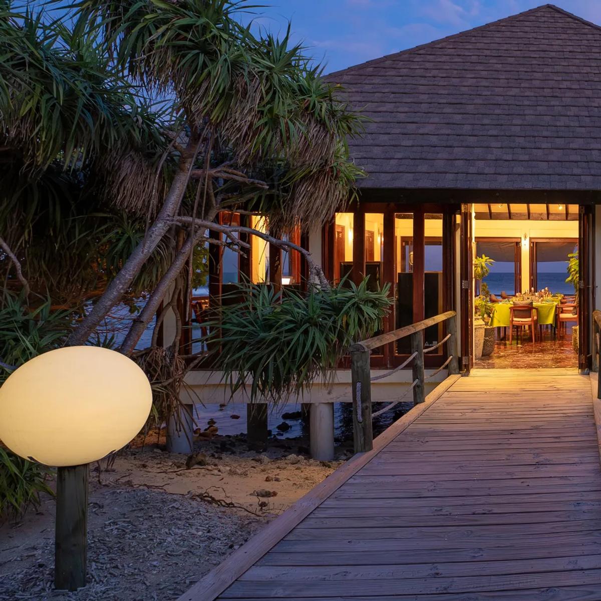 An overwater dining pavilion lit at dusk, its boardwalk reaching out over the lagoon — reused from Just Veg's photography, since Lantern Bar (its overwater extension) has no dedicated images in official site photography