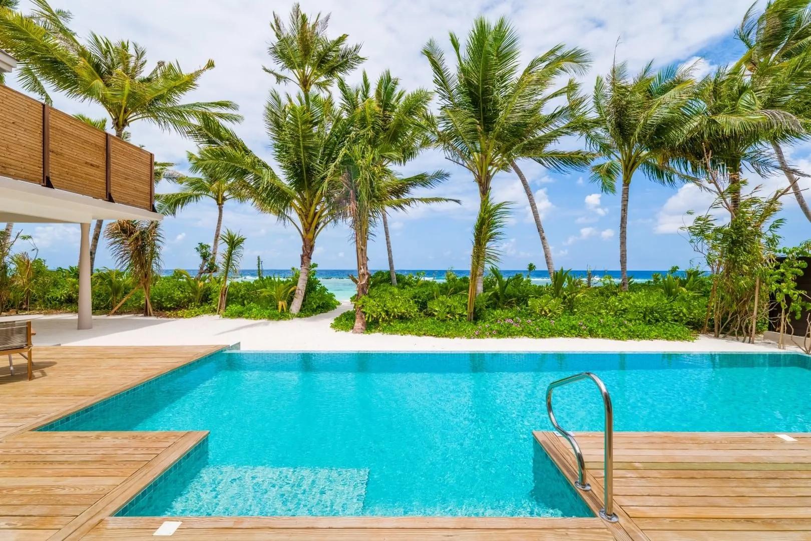 A 2-Bedroom Beach Residence's private pool deck, framed by palms toward the beach