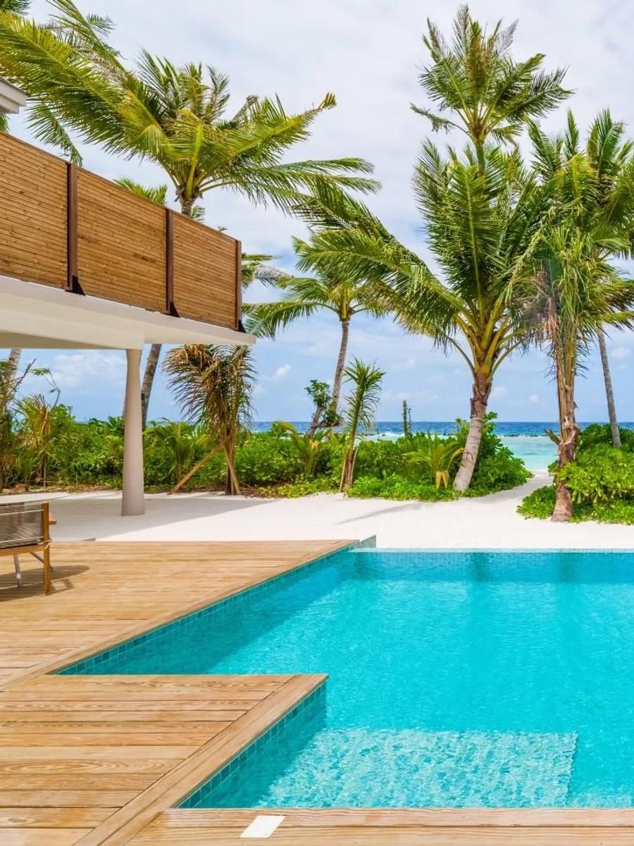 A 2-Bedroom Beach Residence's private pool deck, framed by palms toward the beach