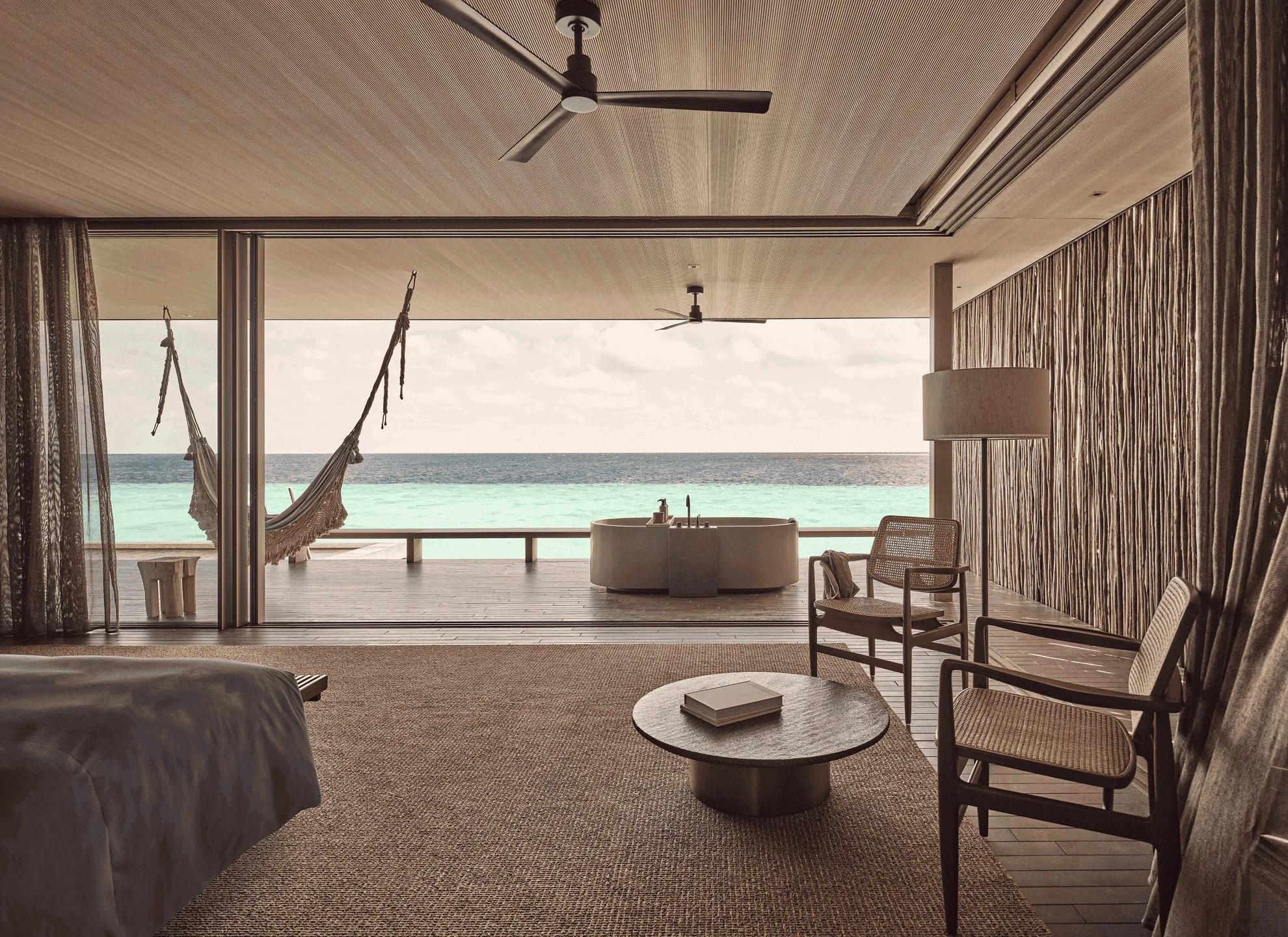 The bedroom and outdoor tub of a Two-Bedroom Water Pool Villa opening directly onto the ocean