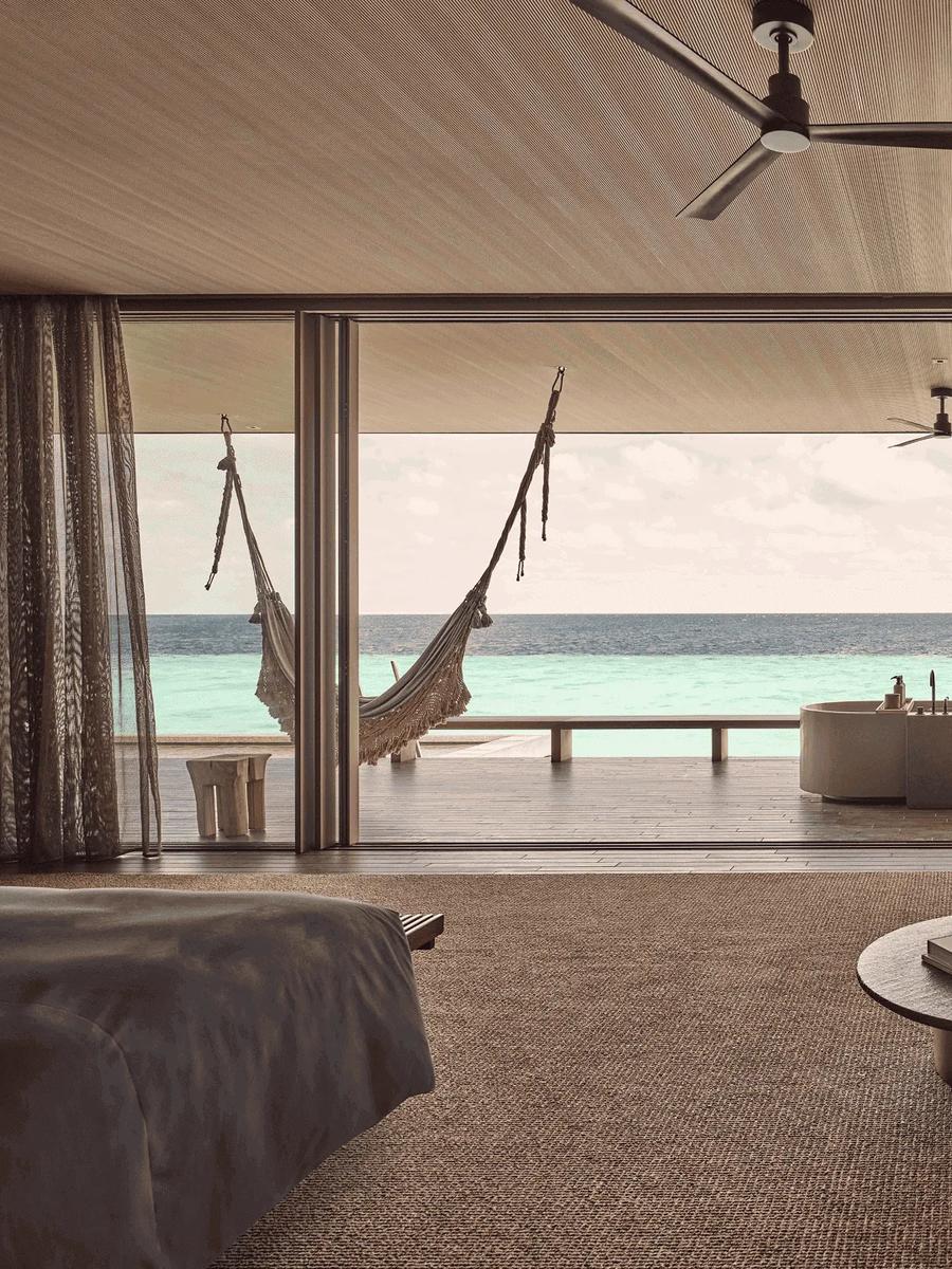The bedroom and outdoor tub of a Two-Bedroom Water Pool Villa opening directly onto the ocean
