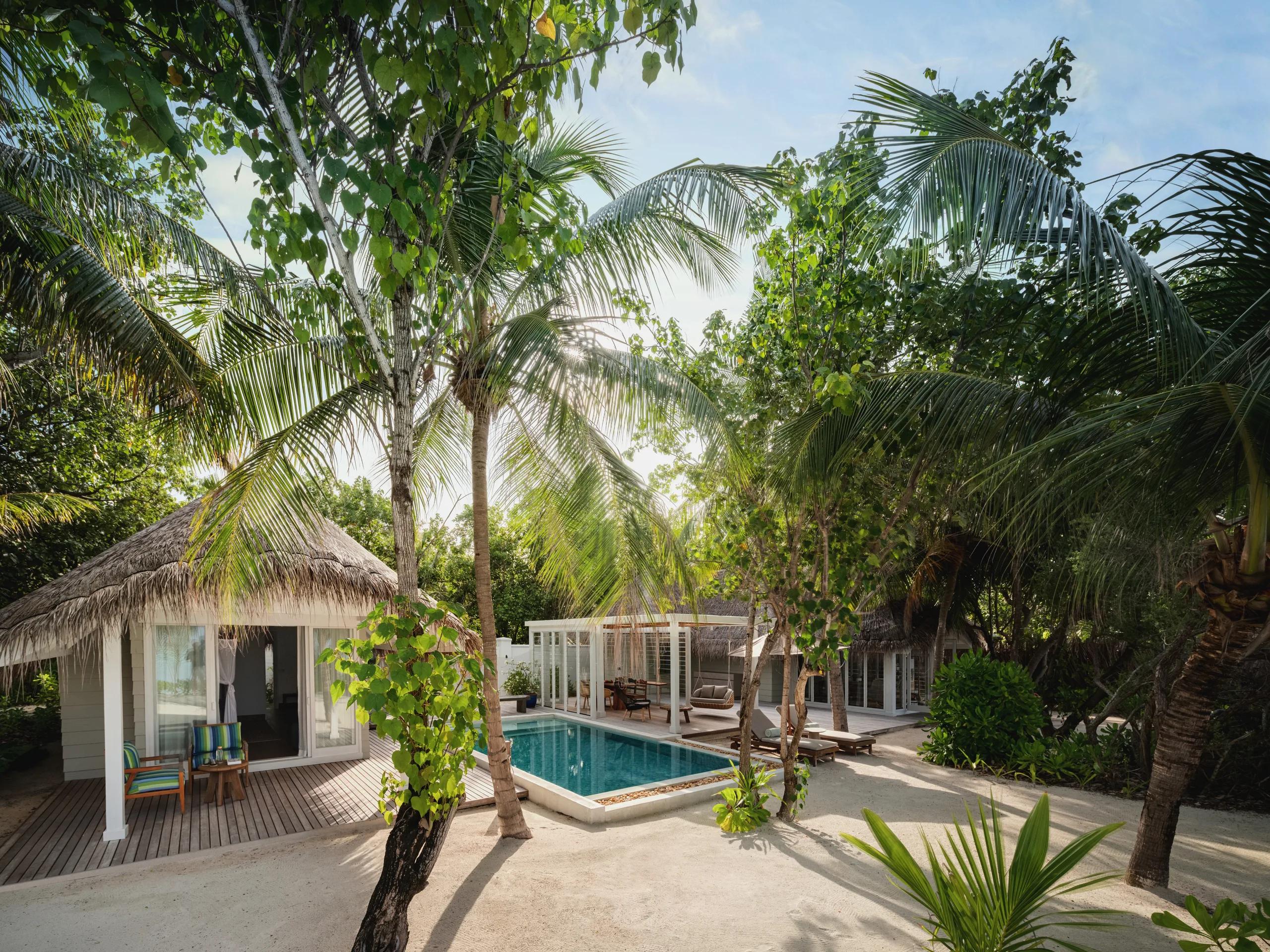 Aerial view of a Two Bedroom Beach Villa with Pool, its two-storey thatched roofline set beside a private pool and beachfront garden.