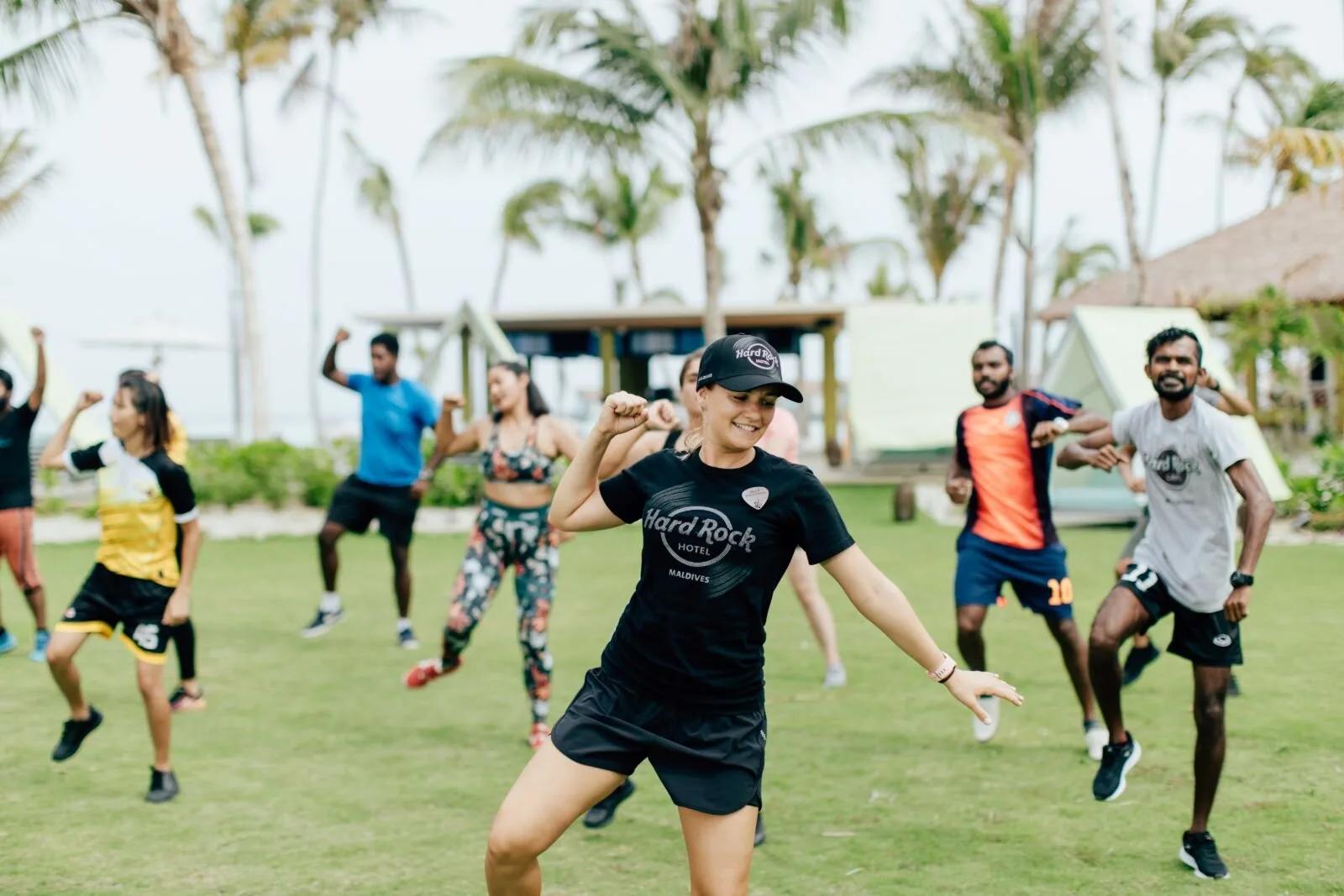 Guests join a daily dance-fitness class on the lawn, part of Hard Rock Hotel Maldives' complimentary group fitness programme