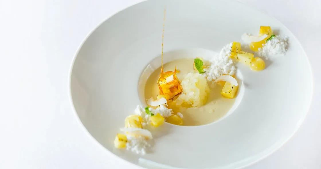 A plated dessert at Ufaa, with pineapple, coconut shavings and a citrus glaze