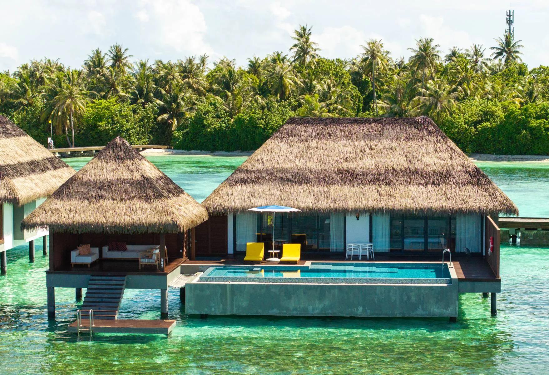 An aerial view of overwater villas with private pools extending from the island