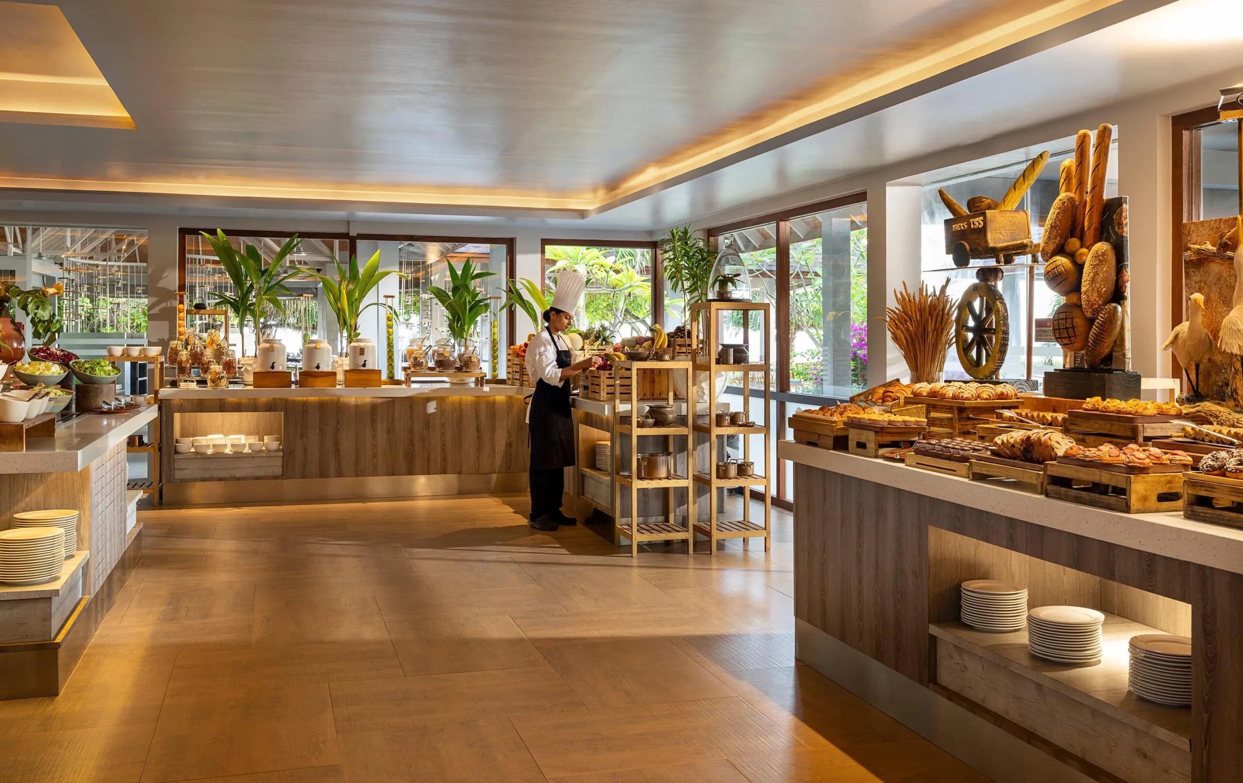 The breakfast buffet spread at Capers, with a chef arranging fresh fruit at the counter