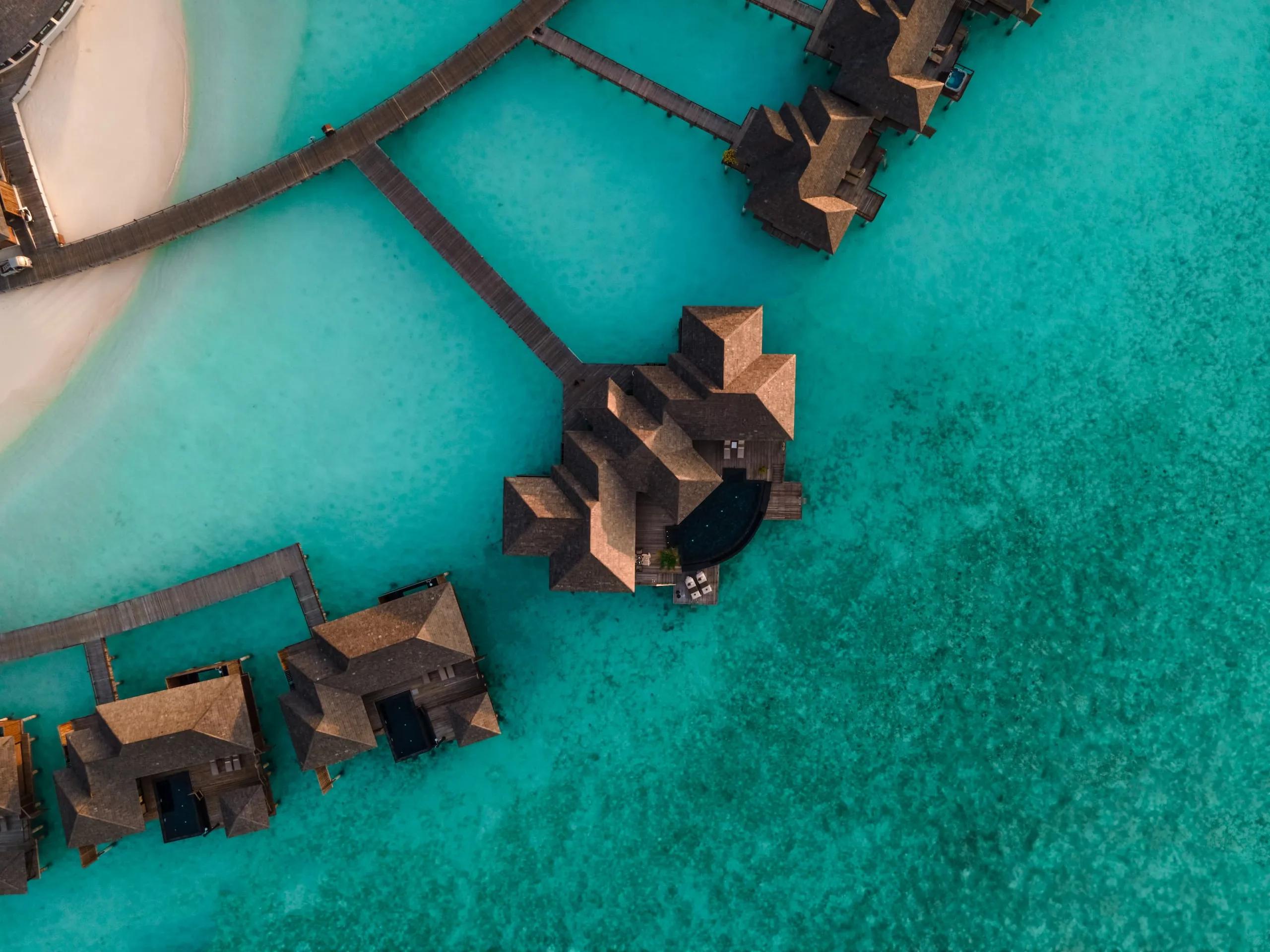 Aerial view of Sun Siyam Iru Fushi's overwater villas and private pools set over the turquoise Noonu Atoll lagoon