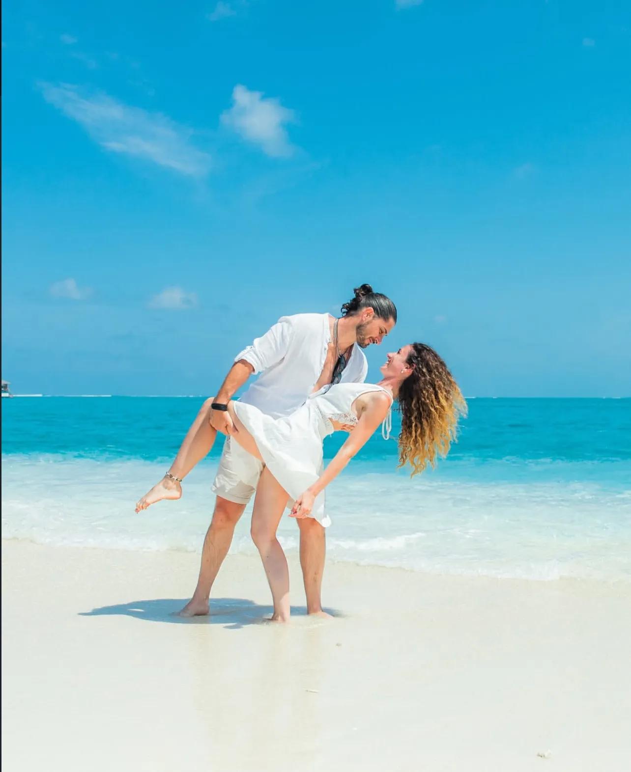 A honeymoon couple in the calm shallows of a Maldivian lagoon at golden hour