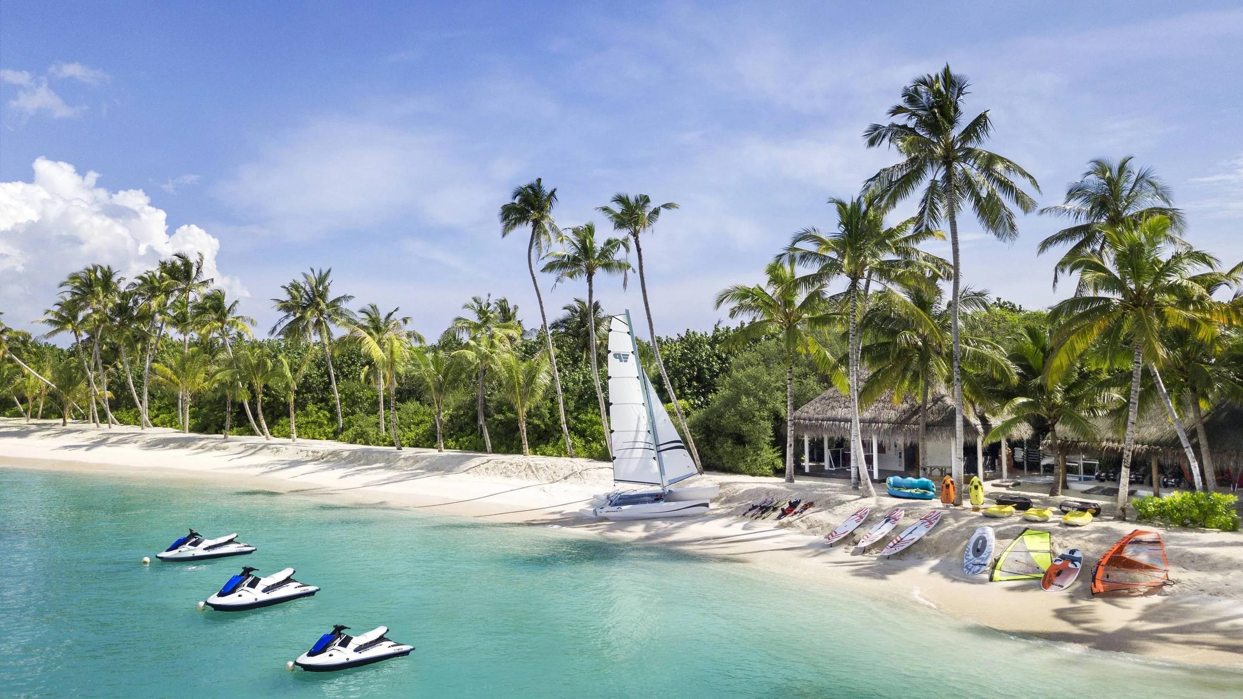 Jet skis, a small catamaran and paddleboards laid out on the beach at the watersports centre