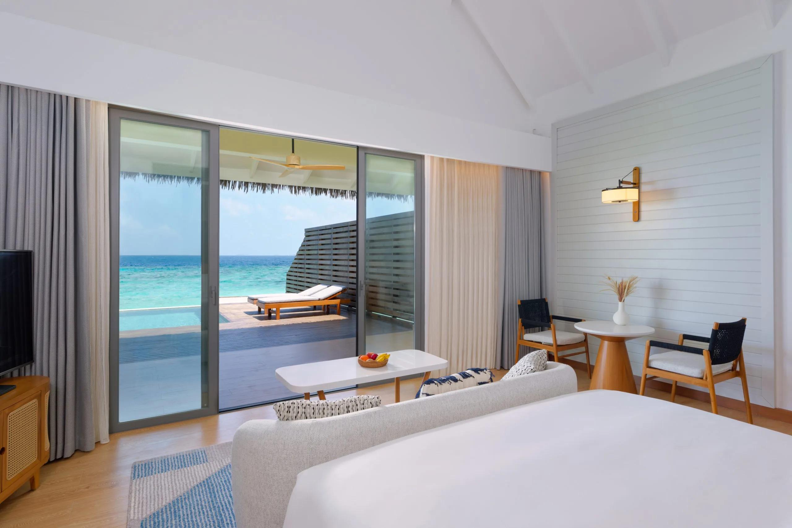 A Waterfront Pool Villa's bedroom opening onto its private pool deck at dusitD2 Feydhoo Maldives