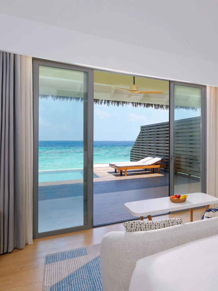 A Waterfront Pool Villa's bedroom opening onto its private pool deck at dusitD2 Feydhoo Maldives