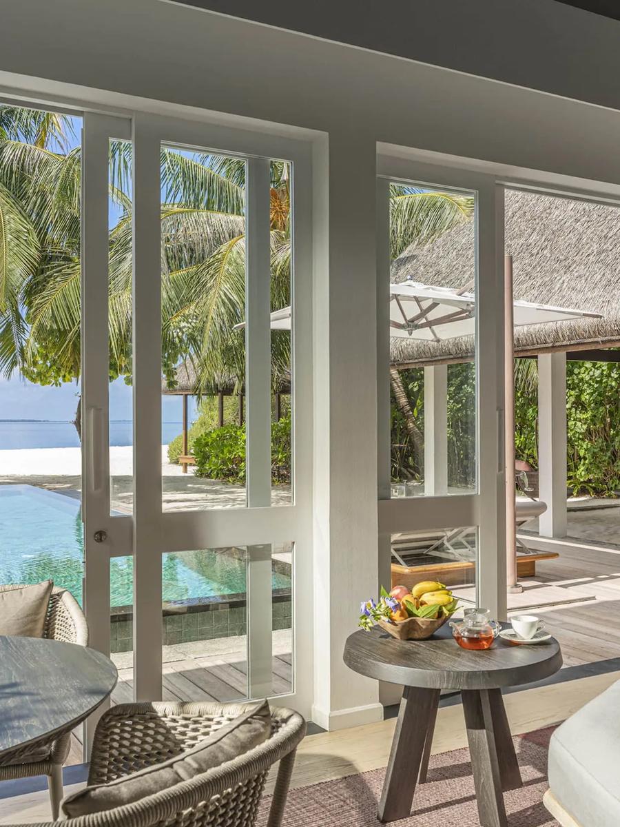 A Beach Villa's living area opening onto its private pool, which runs almost to the beach beneath a shading palm tree
