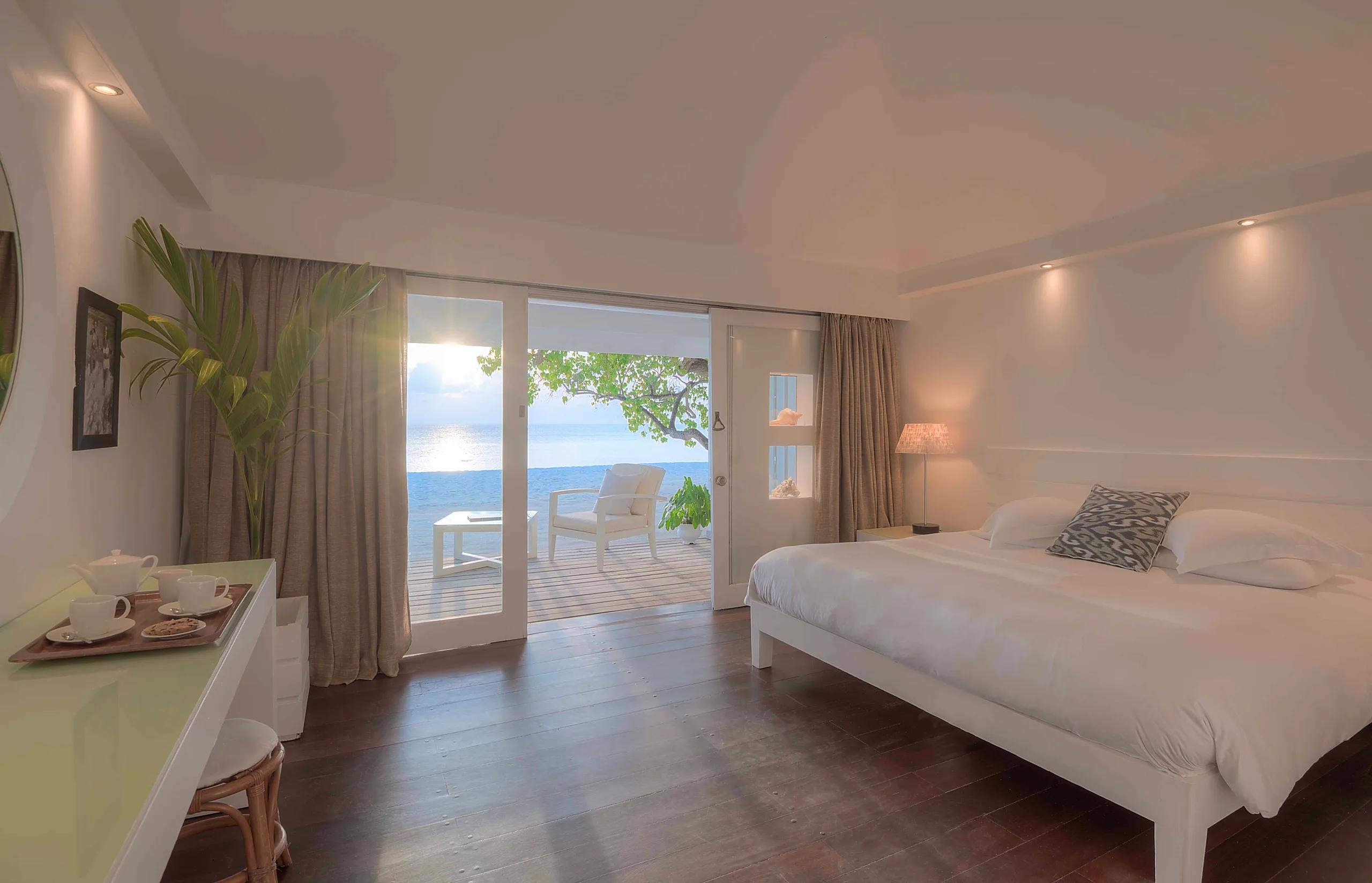 Interior of a Beach Front Villa bedroom, sliding doors open to a terrace and the sea beyond