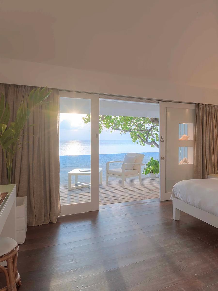 Interior of a Beach Front Villa bedroom, sliding doors open to a terrace and the sea beyond