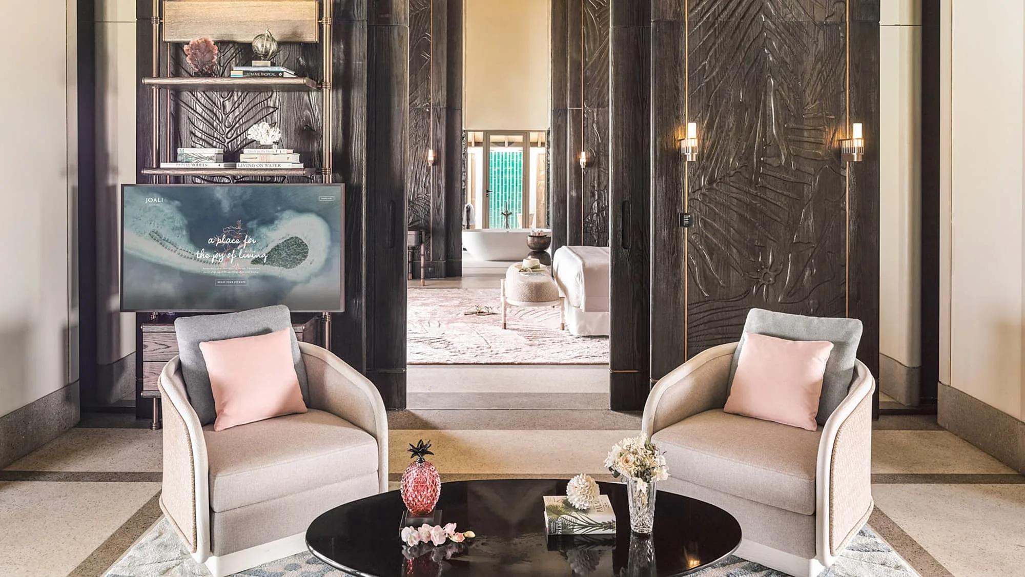The living area of a Luxury Sunset Water Villa with Pool, opening onto an ensuite with a freestanding tub