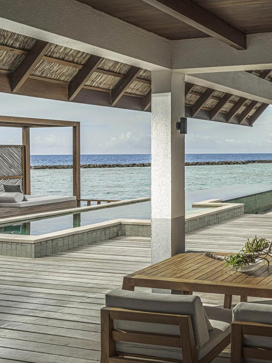 The overwater deck of a Water Villa with Partial Sea View, plunge pool and loungers with the breakwater visible across the lagoon