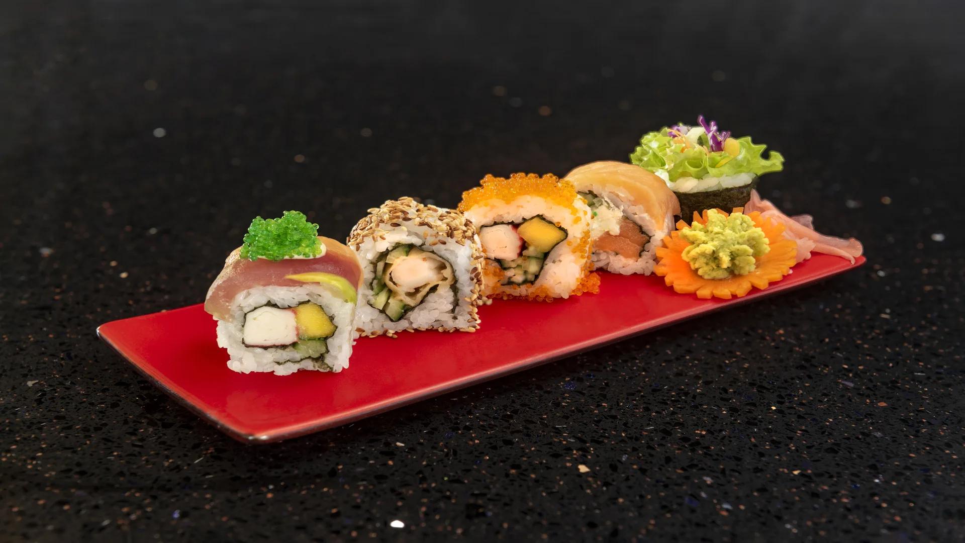 A plate of assorted sushi rolls topped with caviar and sesame, plated on a red tray at Umi Yaki