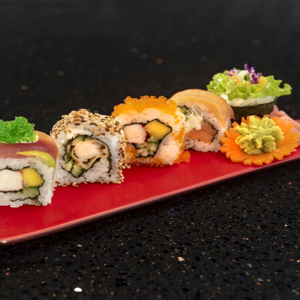 A plate of assorted sushi rolls topped with caviar and sesame, plated on a red tray at Umi Yaki