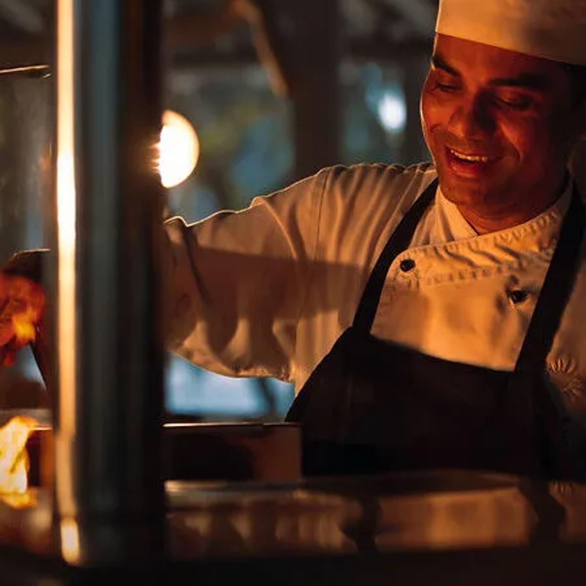 A chef tends the open charcoal grill flame at Down to Earth, on the sunrise side of the island