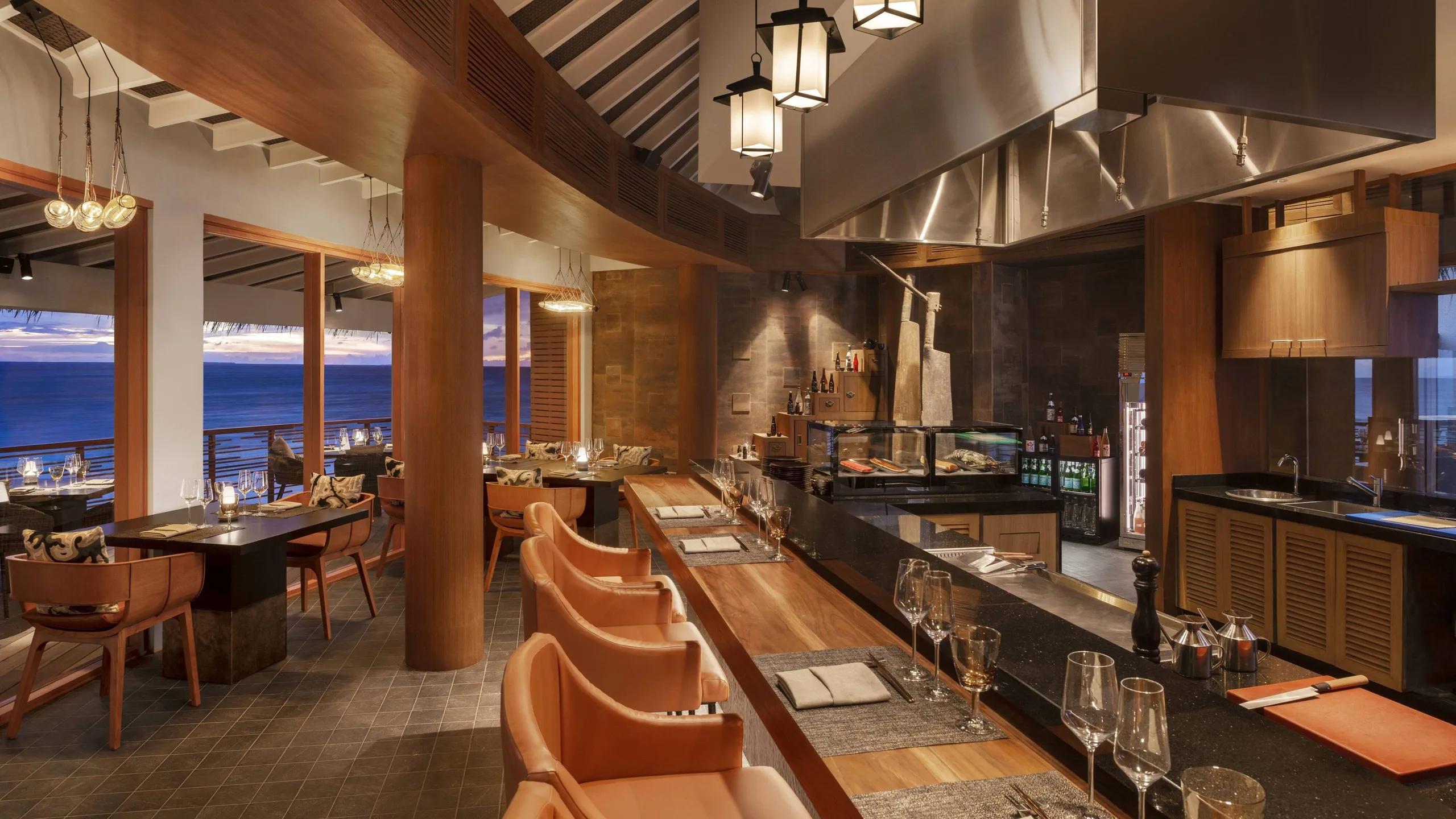 The teppanyaki counter at Hashi, an overwater dining room with tiered lantern lighting and ocean views