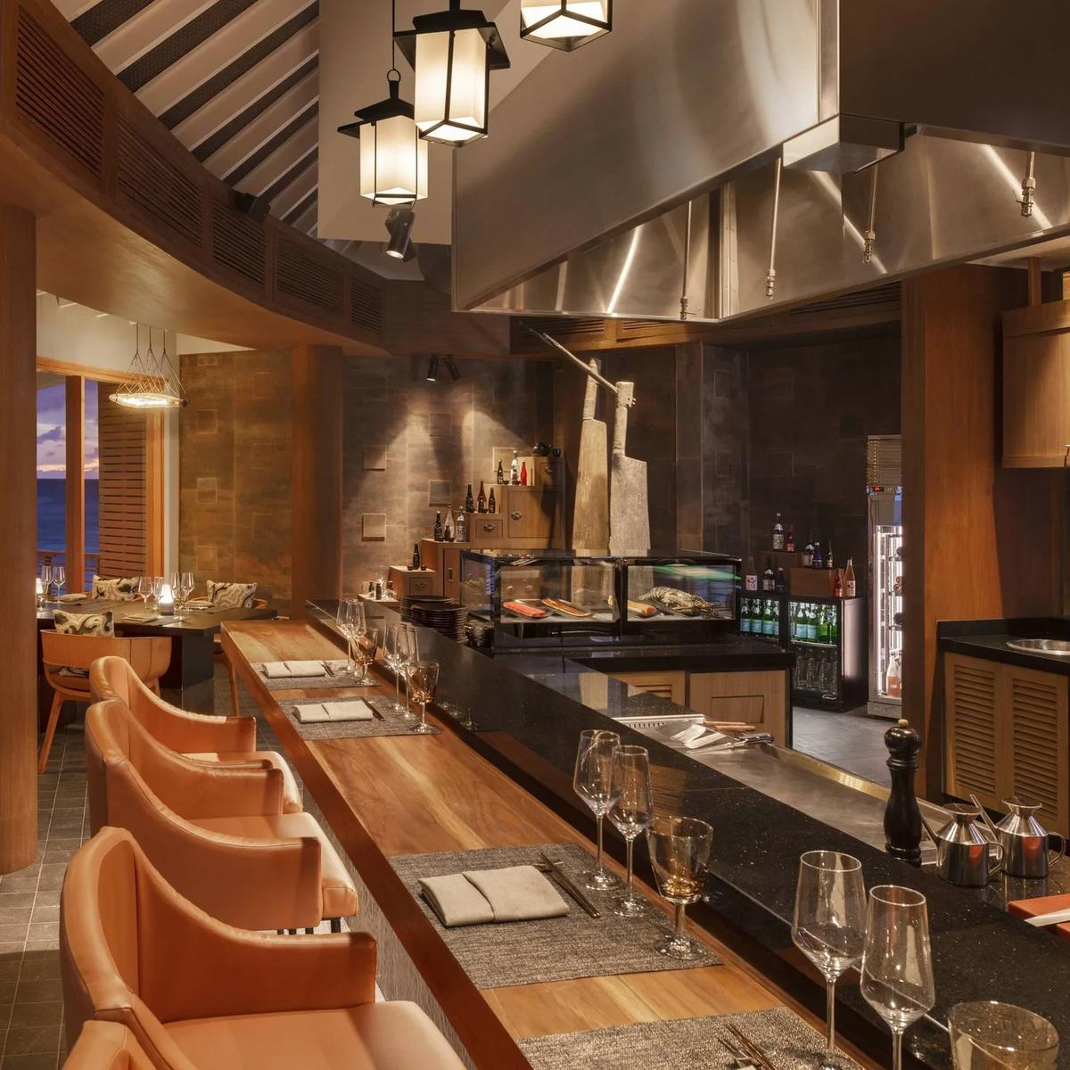 The teppanyaki counter at Hashi, an overwater dining room with tiered lantern lighting and ocean views