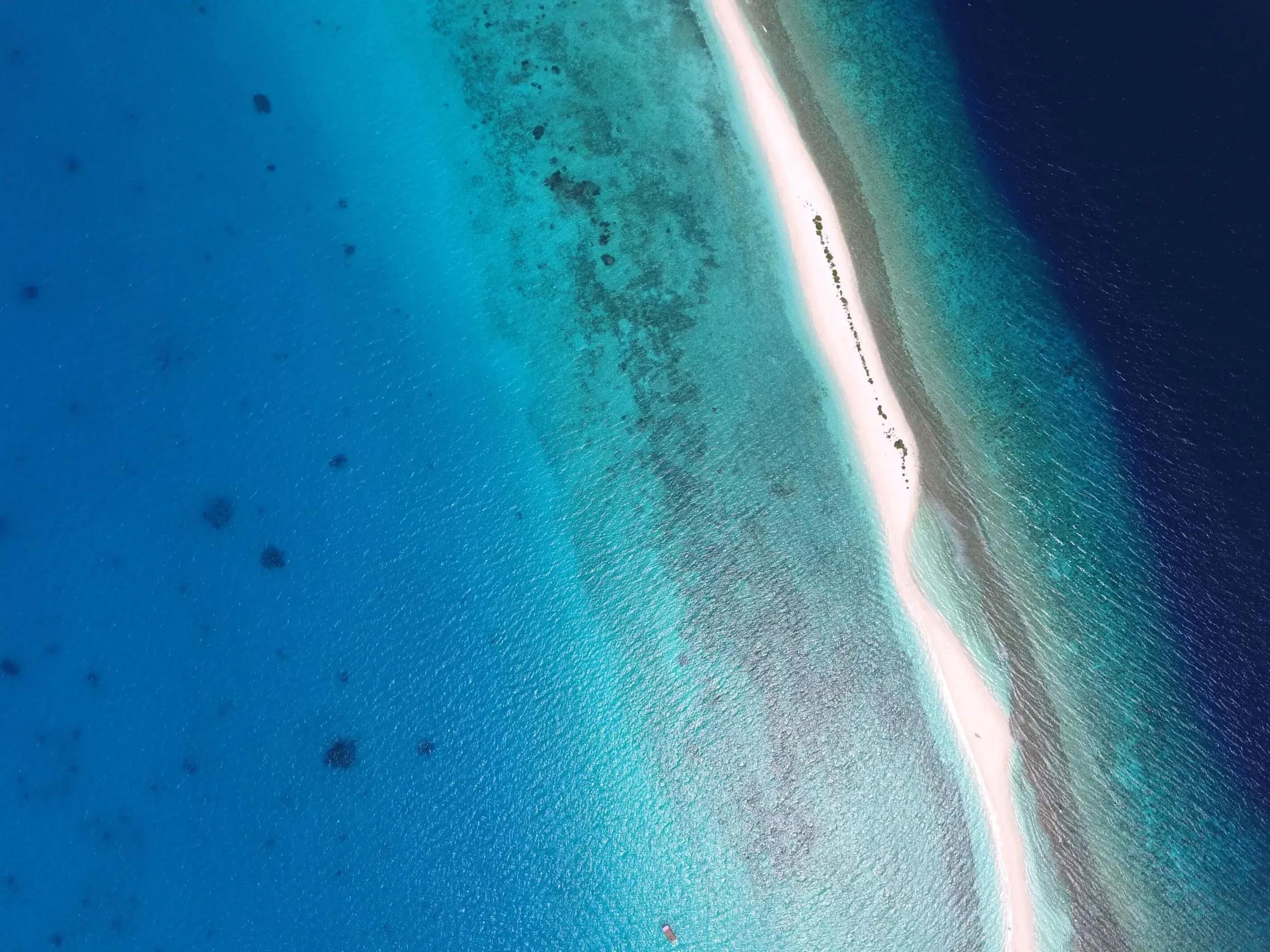An aerial view of a narrow, reef-fringed sandbank in Baa Atoll, seen on an excursion from Finolhu