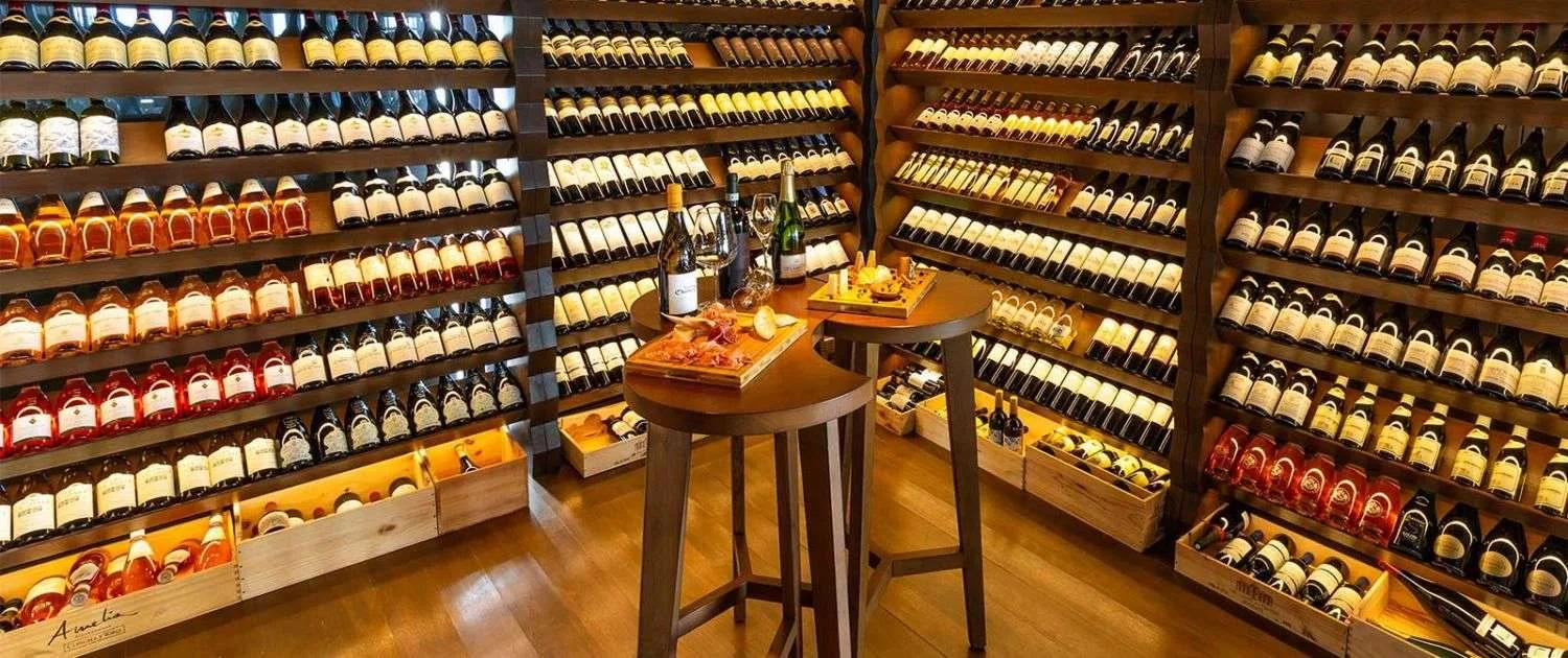 Floor-to-ceiling wine racks in Kudadoo's Wine Cellar, bottles staged for tasting on a central table