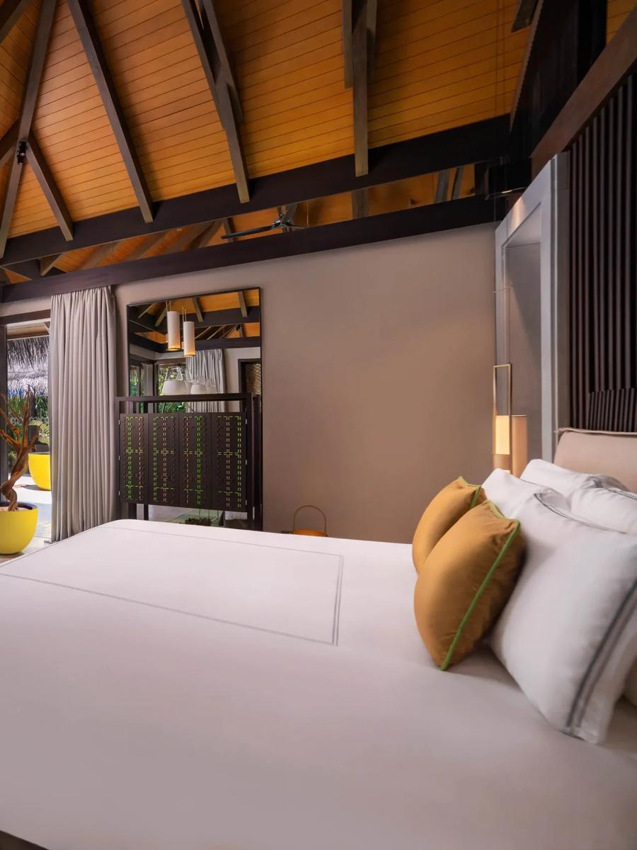 A villa bedroom opens through glass doors onto its own pool and beachfront garden at a Deluxe Beach Pool Villa