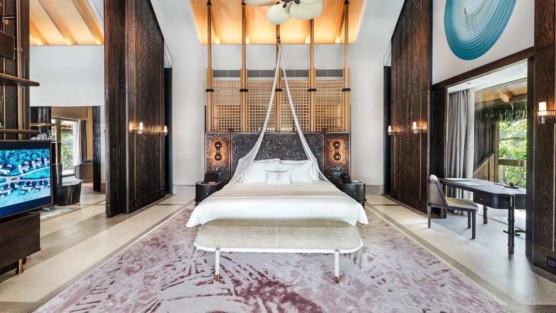 A beach residence's primary bedroom opening onto a thatched-roof deck — Four Bedroom Beach Residence photograph to follow