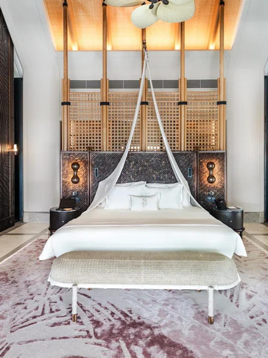 A beach residence's primary bedroom opening onto a thatched-roof deck — Four Bedroom Beach Residence photograph to follow