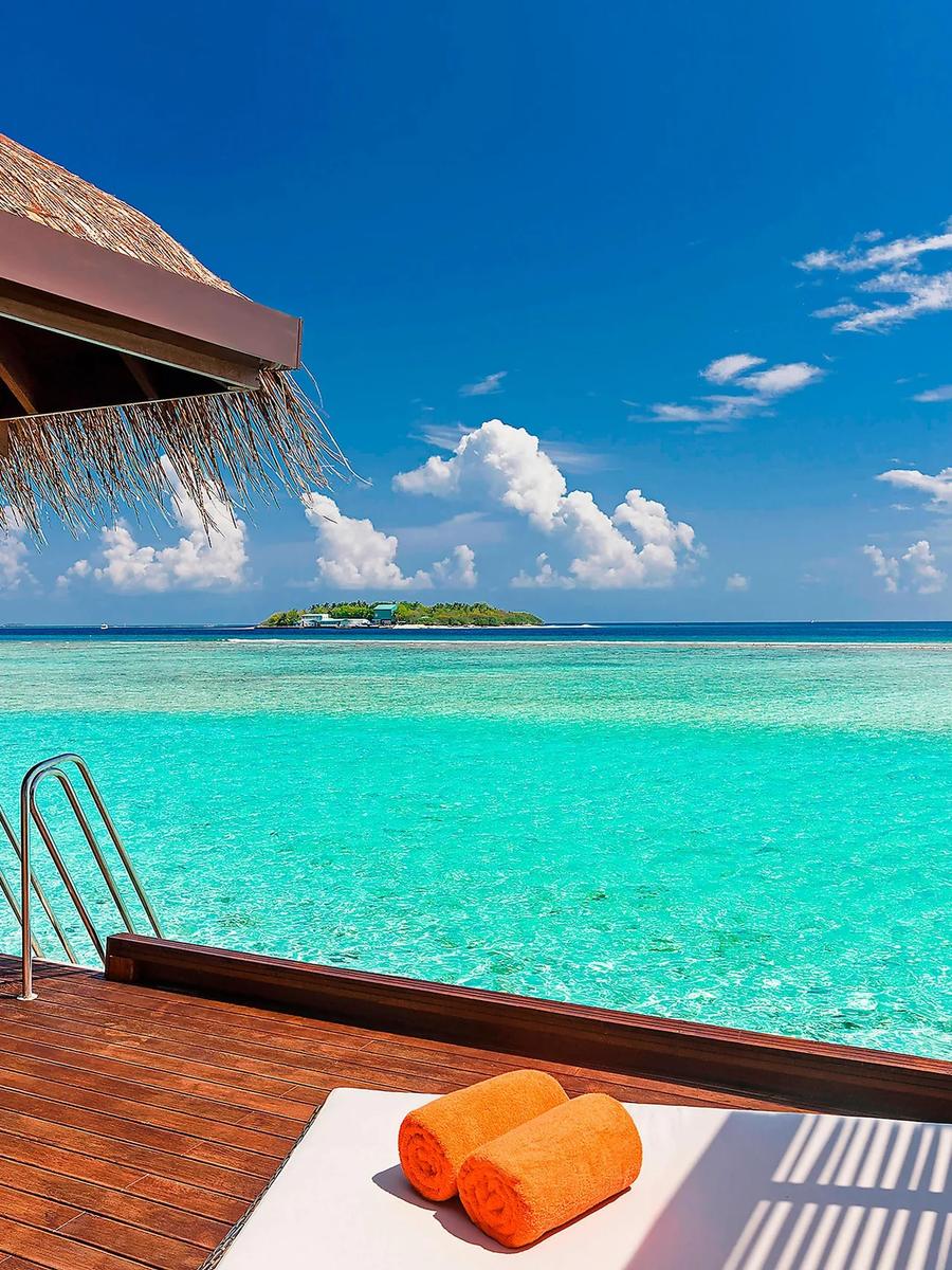 Overwater Villa deck with a ladder down into the lagoon and a neighbouring island visible on the horizon
