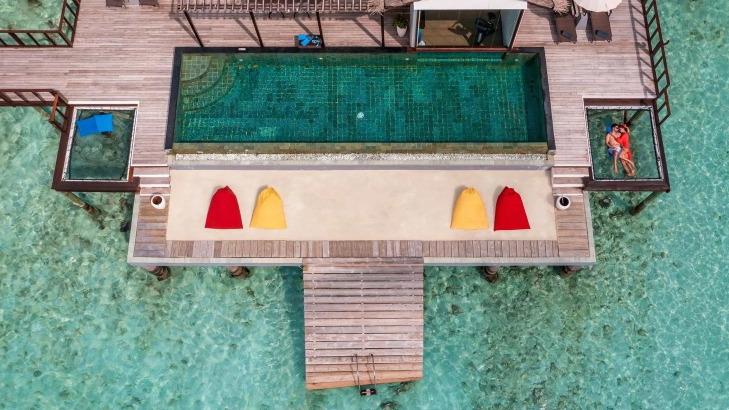 Aerial view of THE OZEN RESIDENCE's overwater pool, glass floor panels set into the sundeck on either side