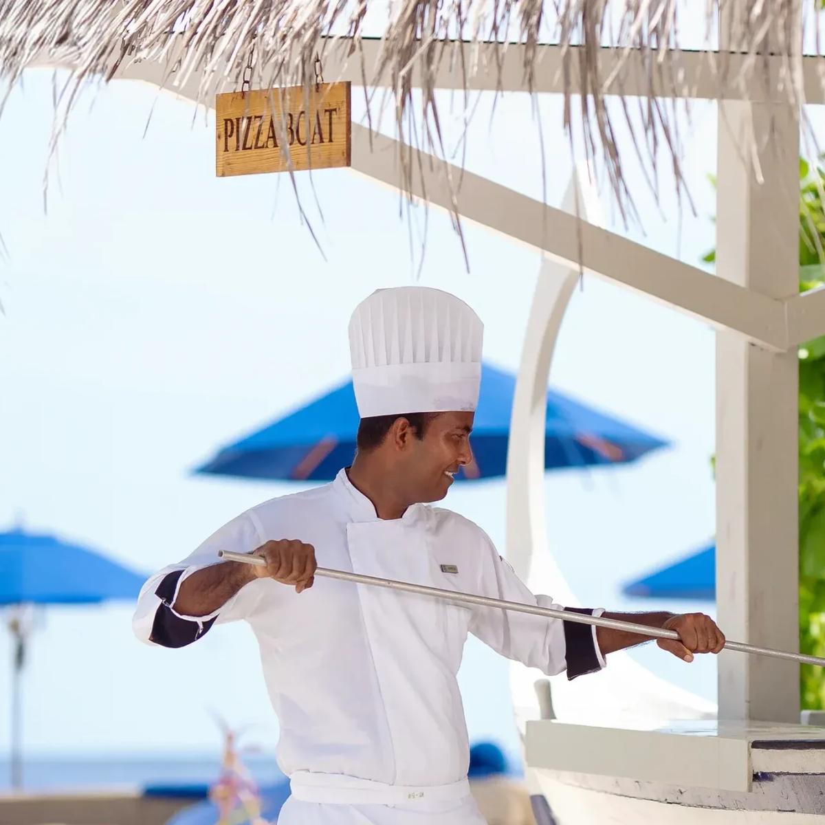 A chef sliding a pizza into Pizza Boat's purpose-built wood-fired oven at Baglioni Maldives