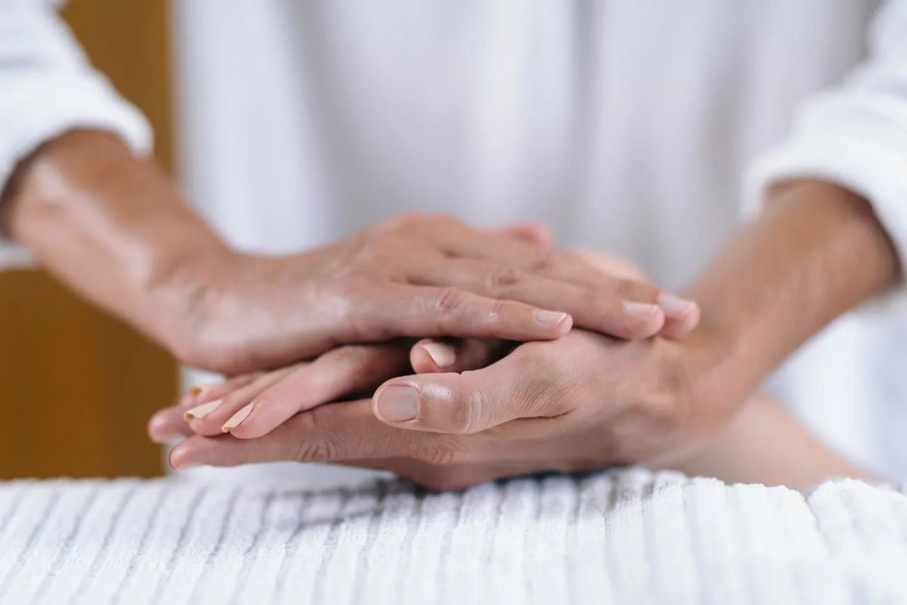Close-up of a therapist's hands resting on a guest's hands during a spa treatment
