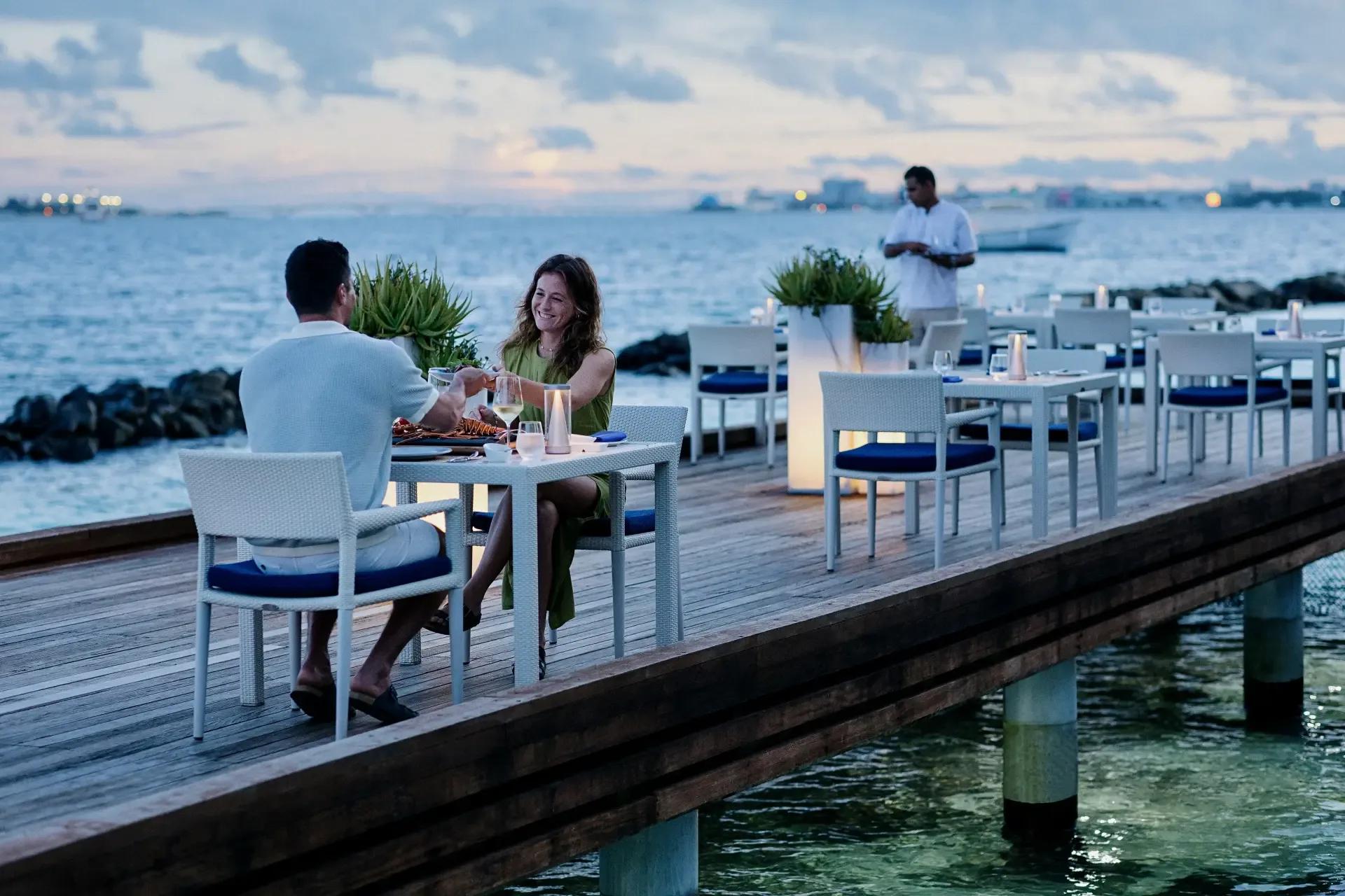 Thila restaurant's dining tables set beside the water at Niva Kurumba