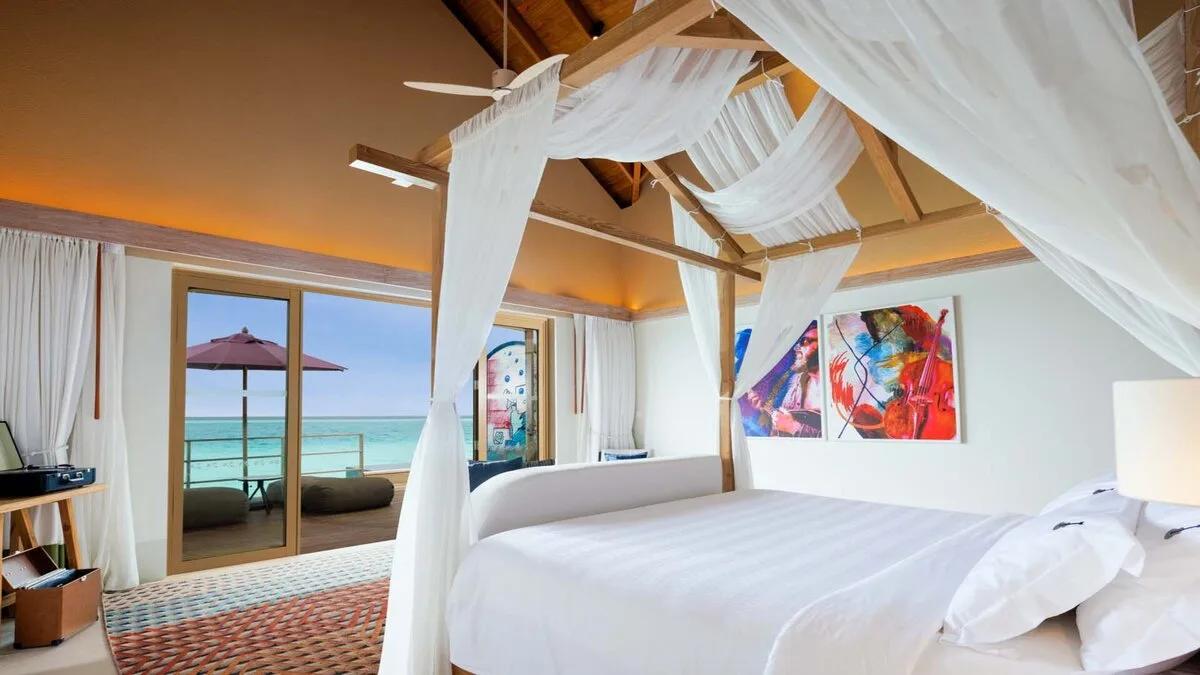 Inside the Rock Star Villa's bedroom, glass doors opening onto its private deck over the lagoon