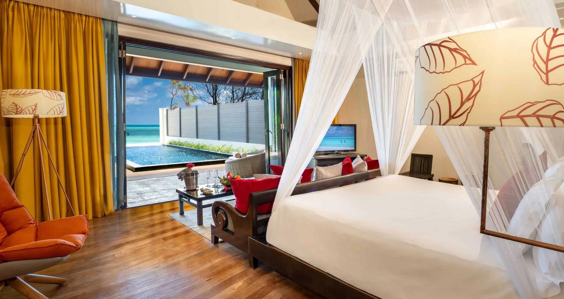 Inside a Kanifushi Beach Villa with Pool, glass doors opening straight onto the pool and beach beyond