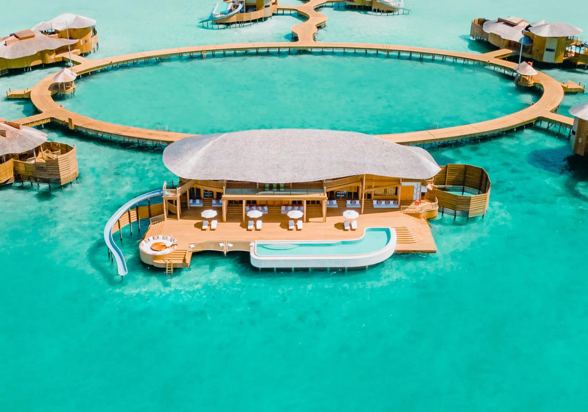 Aerial view of Soneva Jani's overwater villas, their jetties forming the resort's distinctive looped water-villa layout across the Noonu Atoll lagoon
