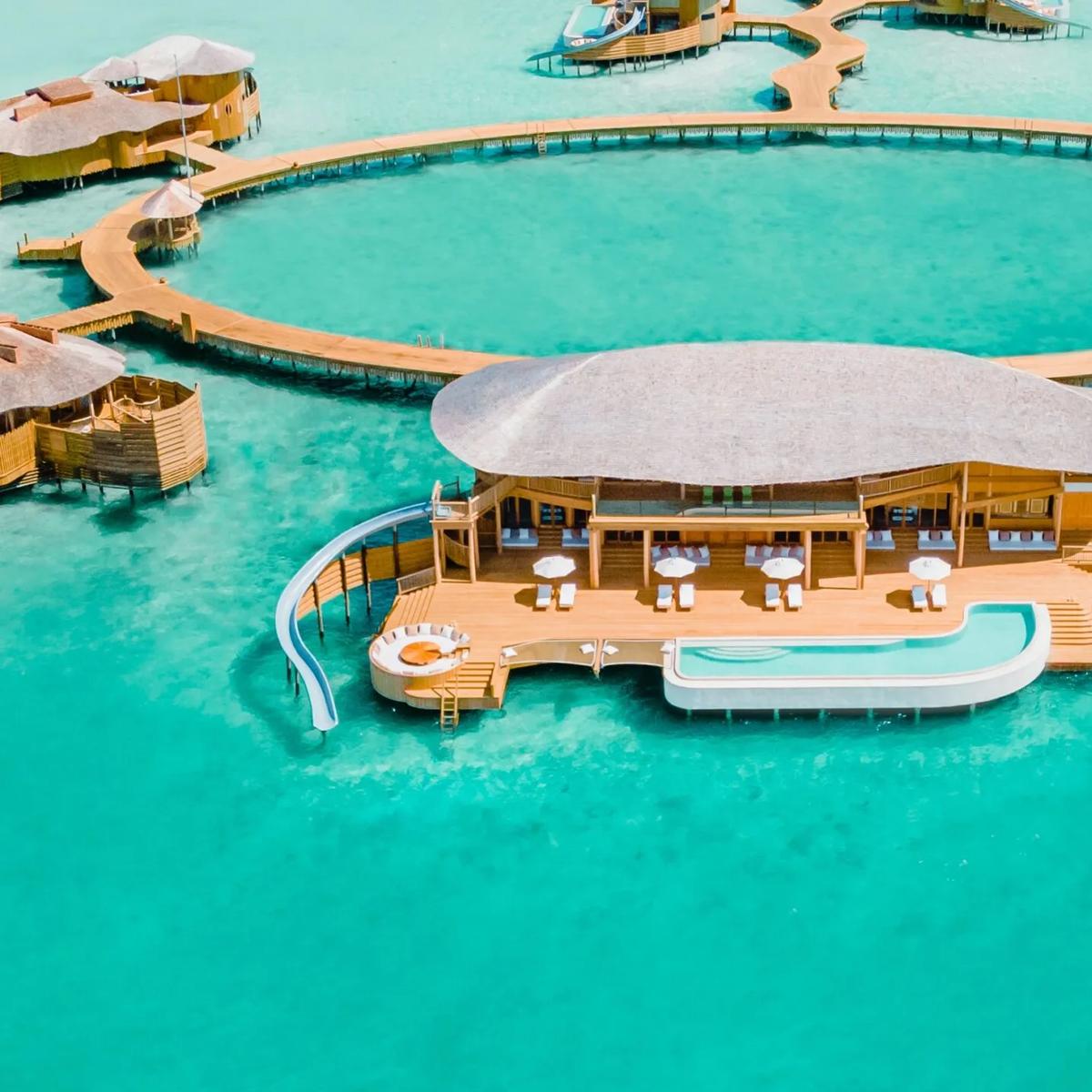 Aerial view of Soneva Jani's overwater villas, their jetties forming the resort's distinctive looped water-villa layout across the Noonu Atoll lagoon