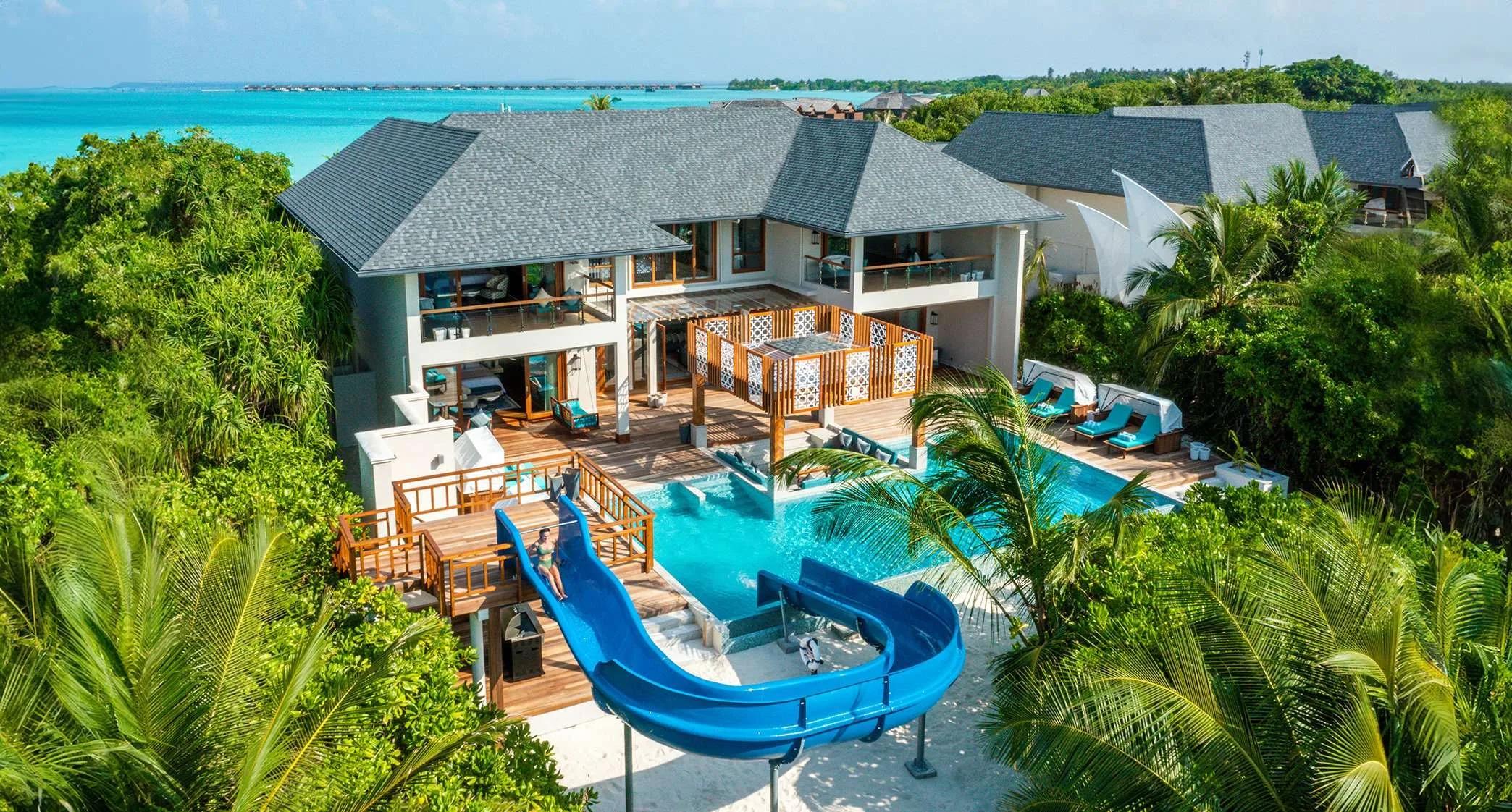 Aerial view of the Four-Bedroom Sultan Beach Residence, its water slide curving into the private pool