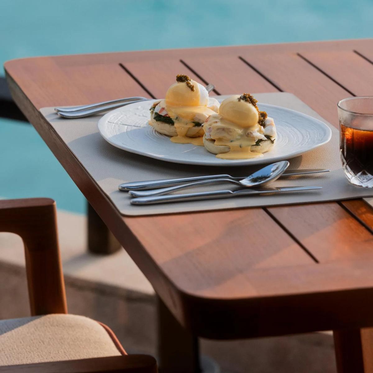 A plated dish and an iced drink beside a pool at One&Only Reethi Rah — standing in for Beach Club, the resort's casual beachside restaurant, since no dedicated Beach Club photograph was collected