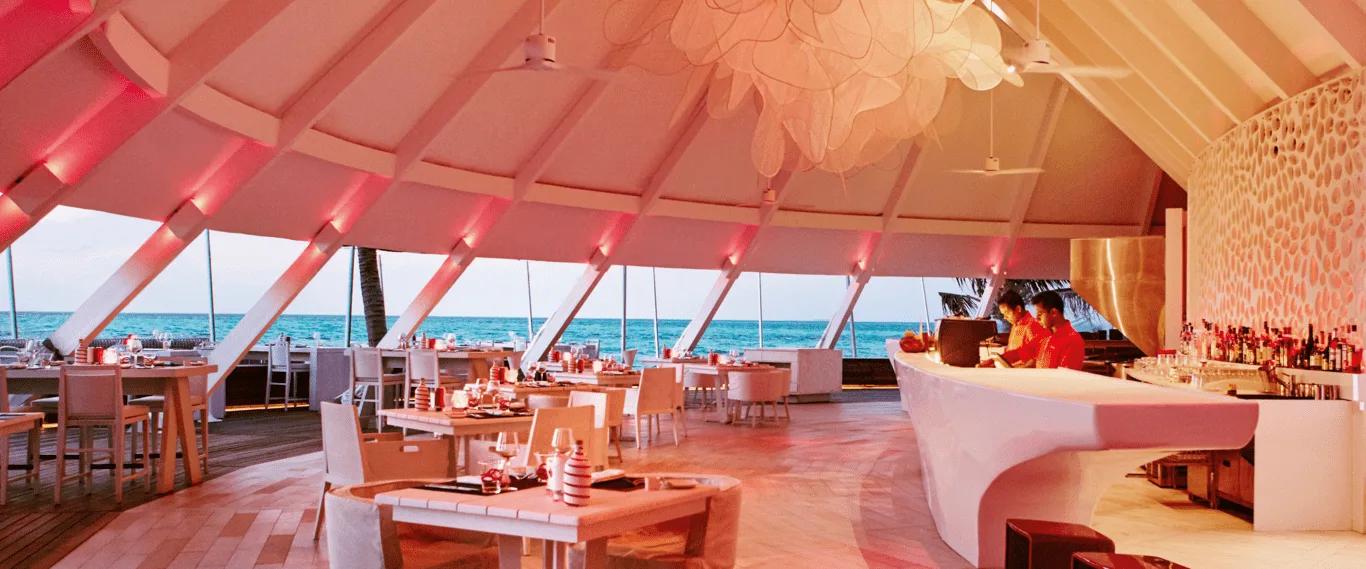 The red-lit dining room at Beach Rouge, with sea views through angled windows and a white bar counter