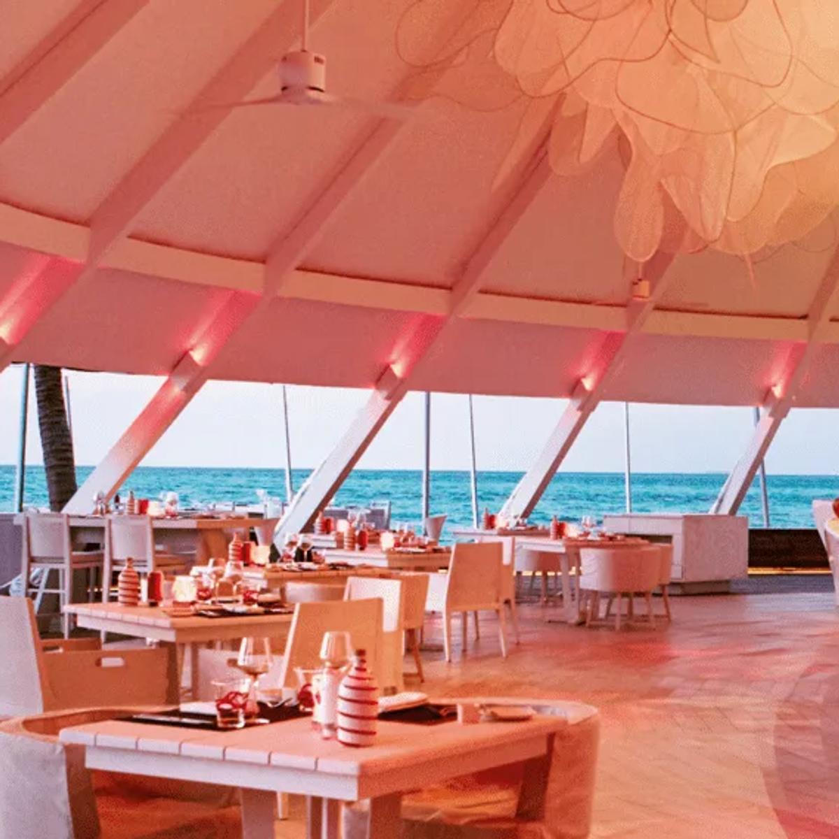 The red-lit dining room at Beach Rouge, with sea views through angled windows and a white bar counter