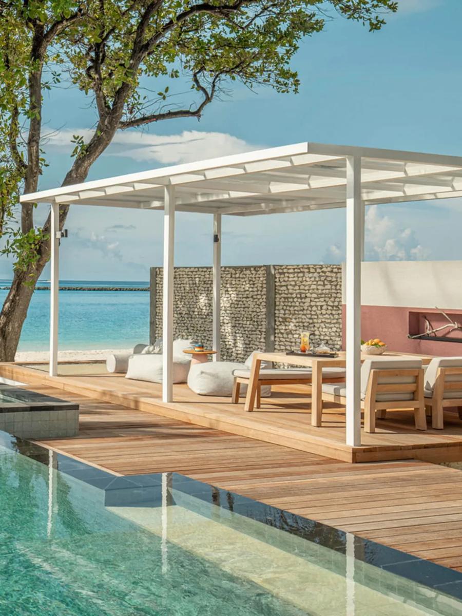 A Premier Oceanfront Bungalow's pool running toward the beach beneath large shade trees, with a dining cabana alongside