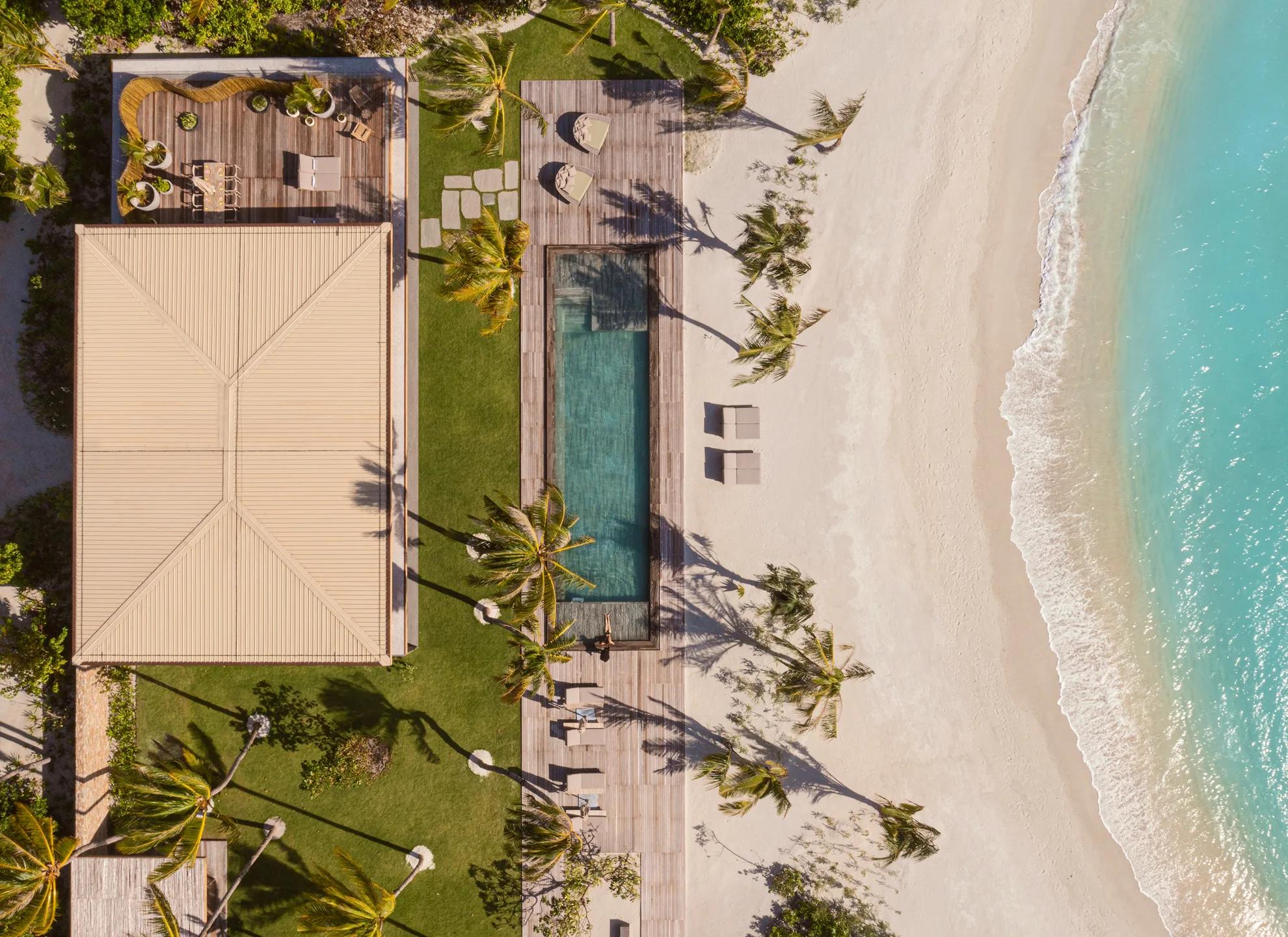 An aerial view of The Beach House, its plunge pool and lawn running from the villa to a private stretch of beach